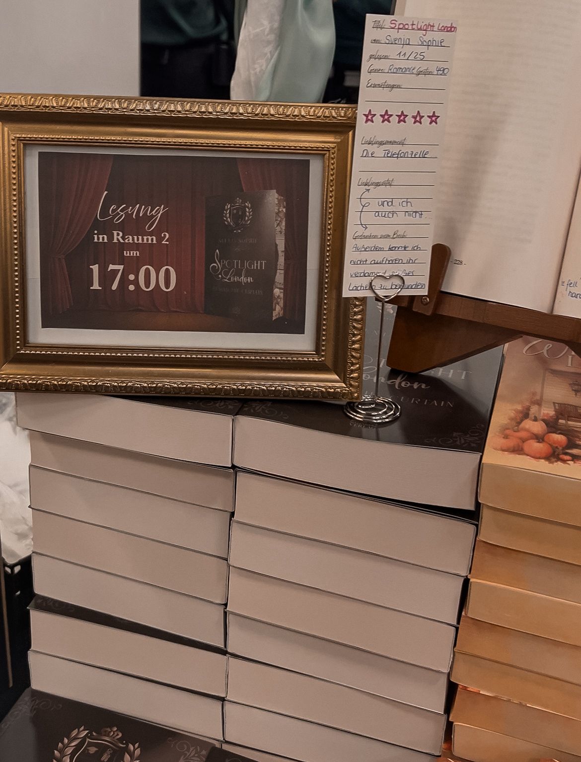 Stapel signierter Buchausgaben mit Hinweisschild zur Lesung um 17:00 in Raum 2